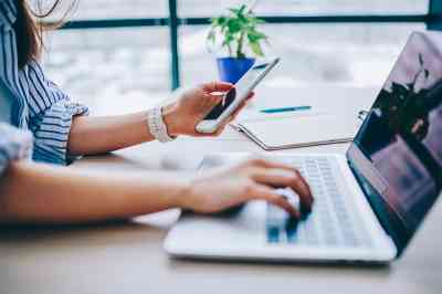 Frau mit Smartphone und Laptop - © BullRun - Adobe Stock.com